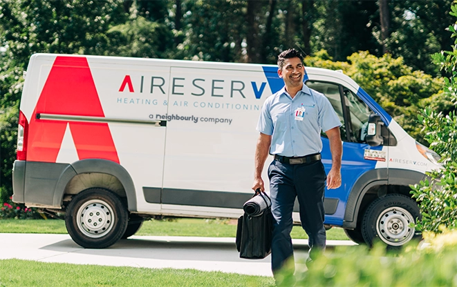 AireServ tech standing next to ASV branded vehicle.