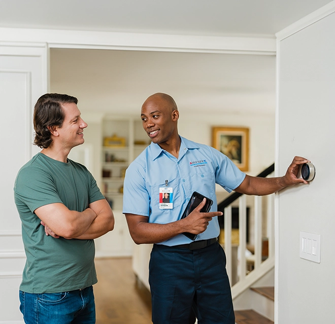 AireServ Technician explaining new thermostat to customer.