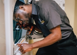 A technician inspects using a flashlight and tools.