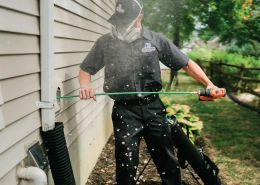 A technician uses a tool to clean a home's exterior.