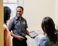 Dryer Vent Wizard technician using tablet to explain services to two female customers.