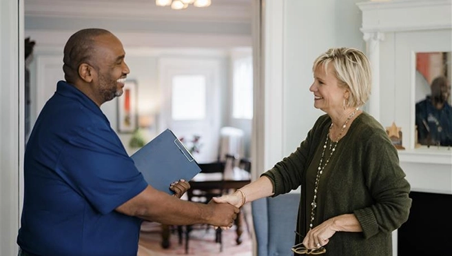 A man is shaking hands with a smiling woman.