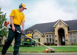 GUY employee cutting grass on a home lawn.