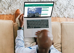 A person using a laptop on a couch, viewing a home-related webpage.