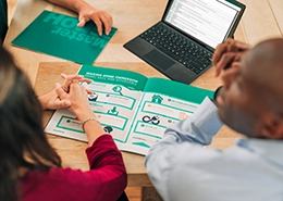 People reviewing printed charts together at a table with a laptop.