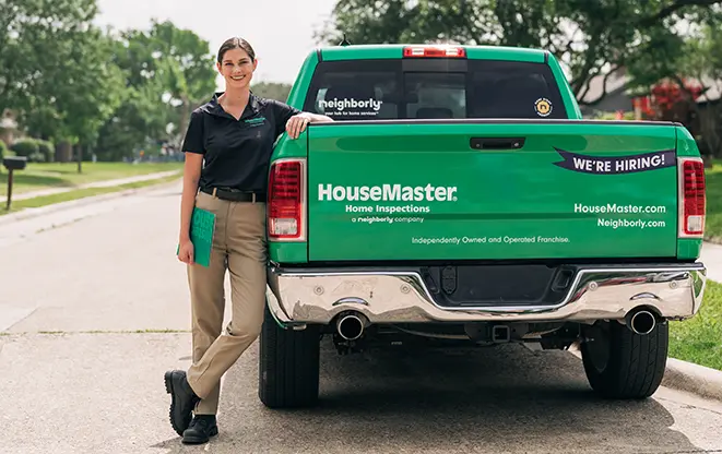 Female HouseMaster inspector leaning on branded vehicle.