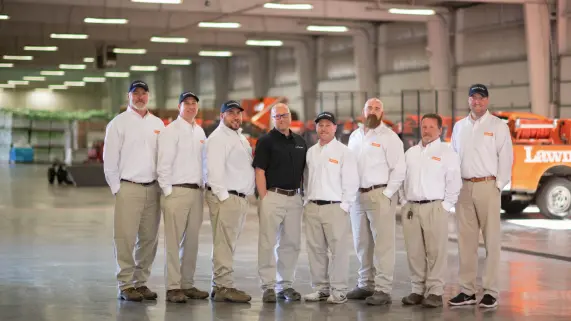 A group of LAP employees standing together inside a large warehouse.