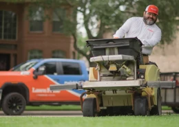 A lawn care worker riding weed equipment onto a green lawn.