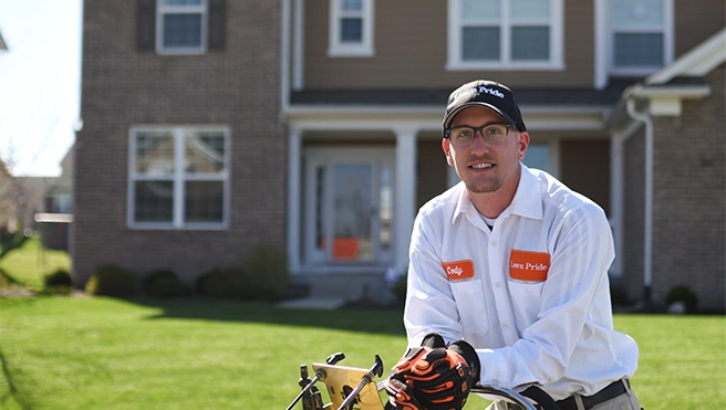 A lawn care technician standing in front of a house.