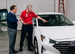 Glass Doctor Employee discussing services with a client in a car showroom.