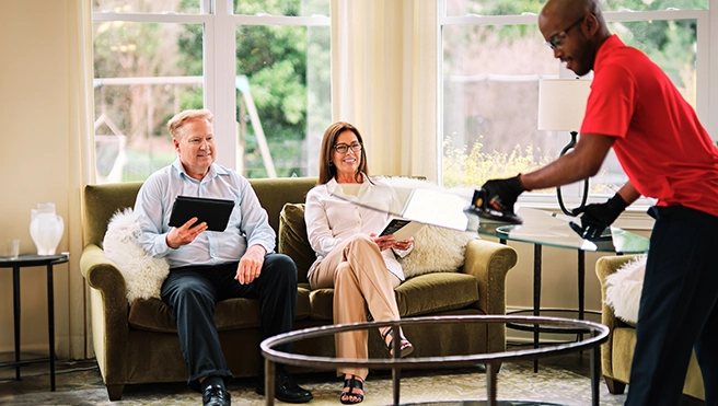 Glass Doctor Employee lifting glass from a small table beside clients.
