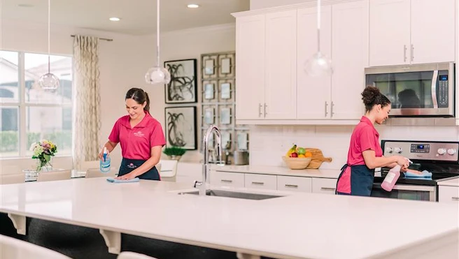 Two MLY service workers wiping surfaces in a modern kitchen.