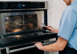 Mr. Appliance Employee applying a sticker to an oven.