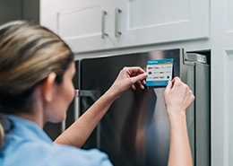 Mr. Appliance employee applying a sticker to a refrigerator.