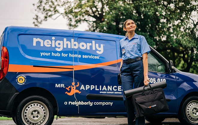 Mr. Appliance technician standing beside a service van.