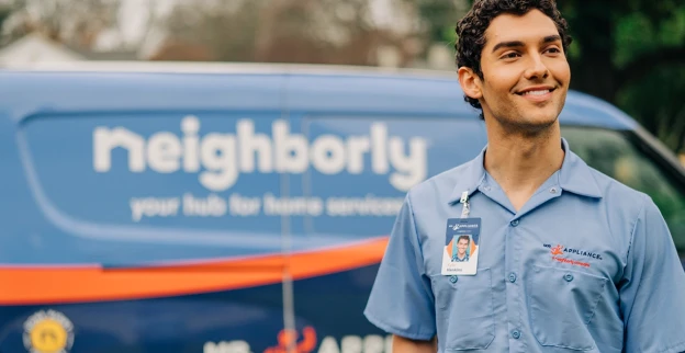 Mr. Appliance technician standing beside a service van.
