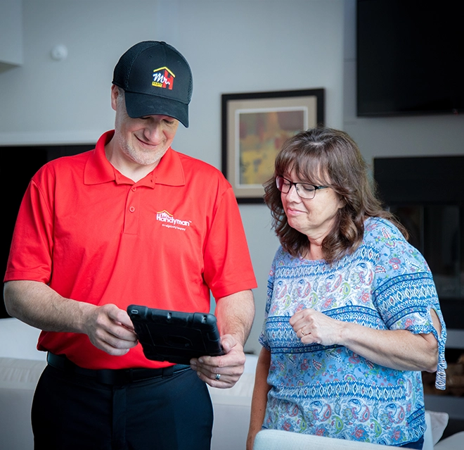 Mr. Handyman technician showing tablet to smiling customer.