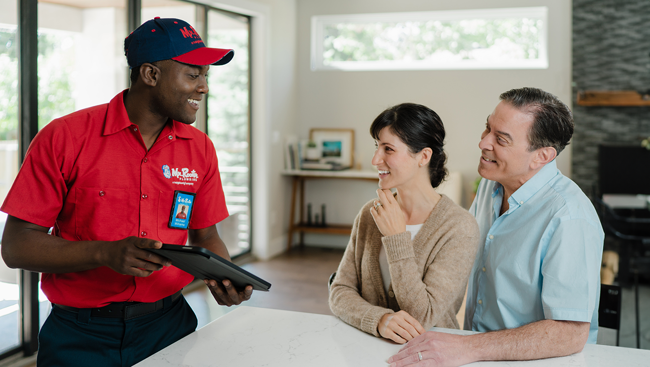 Mr. Rooter plumber explaining service details to a family.