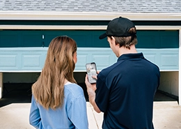 A PDS worker shows something on a phone to a client.