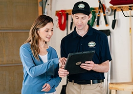 A service professional shows a tablet to a customer in a garage.