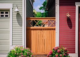 A gate with bushes in front of nearby houses.