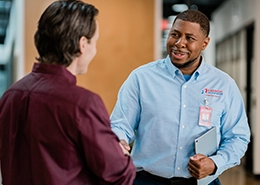 Rainbow Restoration technician in a blue shirt shaking hands with a customer.