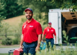 Two technicians carrying equipment for smoke and fire damage restoration.