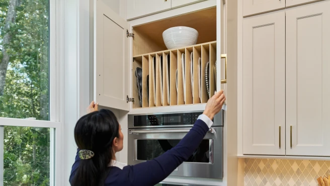 Woman opening kitchen cabinet with custom shelving.