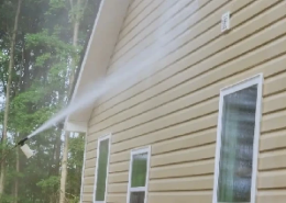 Cleaning the exterior walls of a house with a pressure washer.