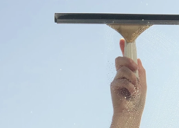 A person cleaning a window with a wiper.