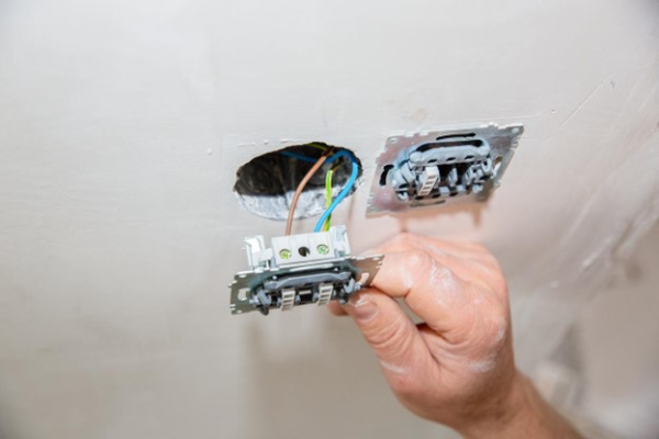 Installing a GFCI outlet with exposed wires in a wall.