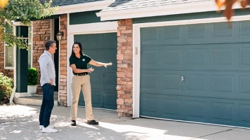Precision Garage Door worker explaining services to customer.