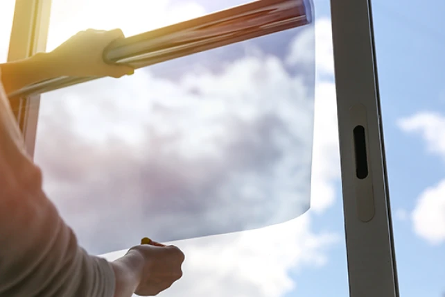 A person applying window film to a glass window.