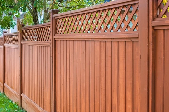 A wooden privacy fence with vertical slats and lattice panels on top.