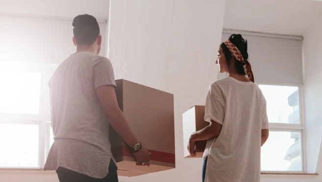 Two persons carry cardboard boxes.