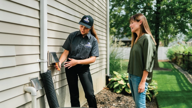 A technician shows a homeowner an exterior house fixture.