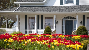 Two story white home with red and yellow tulips in front.