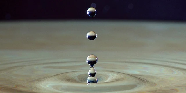 Droplets of water falling into puddle.