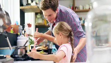 father and daughter cooking in kitchen.