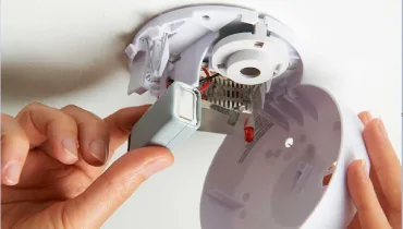 Installing battery into smoke alarm.