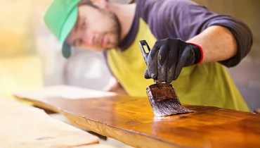 Man staining a piece of wood.