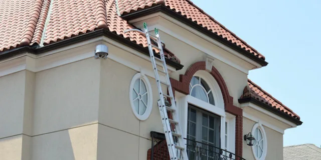 Ladder against top floor of Spanish style home.