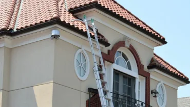 Ladder against top floor of Spanish style home.