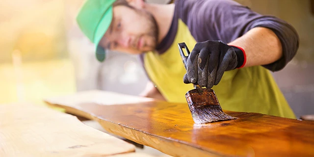 man staining a piece of wood