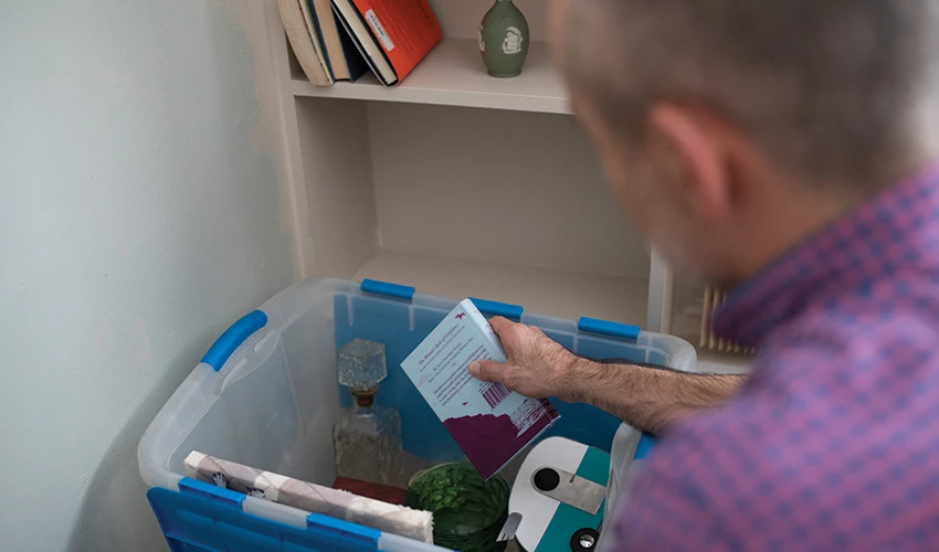 Man packing household items in a tote