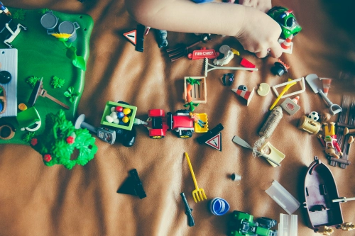 child playing with toys scattered on the ground