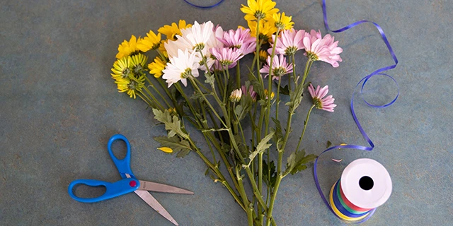 bouquet of flowers on table with scissors and blue string