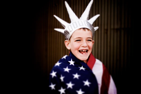 Young boy dressed in American flag and Statue of Liberty crown.