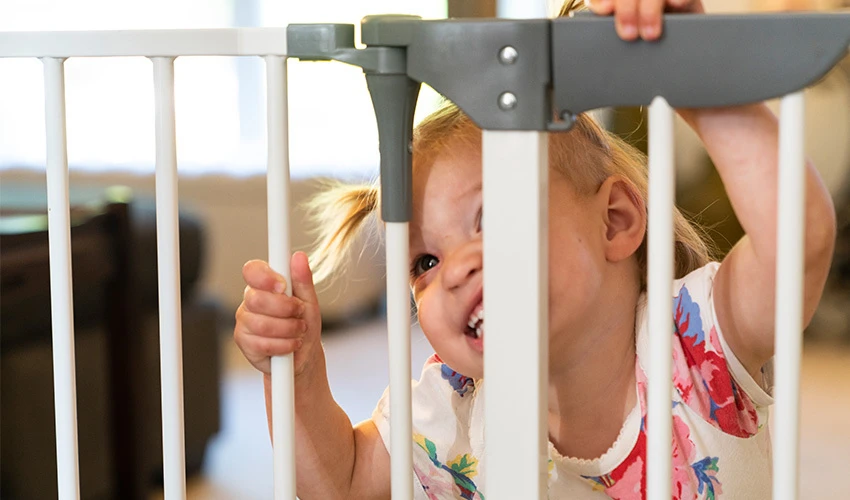 toddler looking through a baby gate