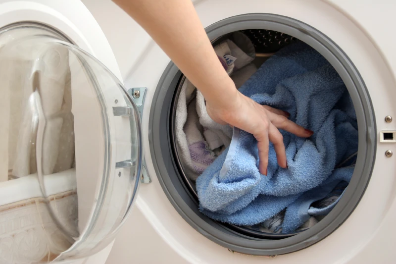 hand placing towels in dryer